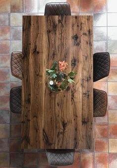 an overhead view of a wooden table with chairs and a potted plant on it