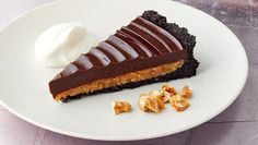 a piece of chocolate pie on a white plate with whipped cream and walnuts next to it