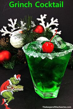 a green drink with cherries in it next to christmas decorations