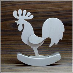 a white rooster figurine sitting on top of a wooden table next to a wood wall