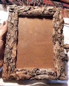 a person is holding up a frame made out of wood and paper with the edges cut off