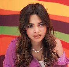 a young woman posing for a photo in front of a colorful wall