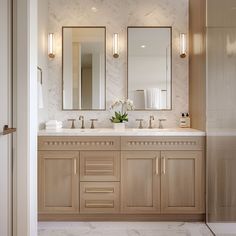 a bathroom with two sinks, mirrors and lights on the wall above them is shown