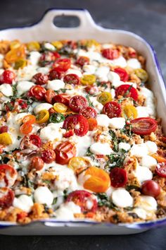 a casserole dish with tomatoes, mozzarella and other toppings