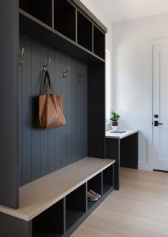 a wooden bench sitting next to a wall with hooks on it's sides and a purse hanging from the back