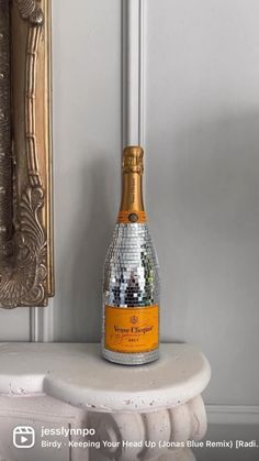 a bottle of champagne sitting on top of a white table next to a mirror frame