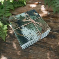 a set of four coasters with green leaves on them sitting on a wooden table