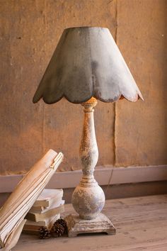 a lamp sitting on top of a wooden table next to a book and a pine cone