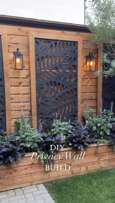 a wooden fence with some plants and lights on the top, along with other flowers