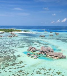 an aerial view of the ocean with over water houses and corals in the foreground