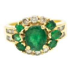 Emerald and diamond 18k yellow gold ring with a contemporary band that has 6 round channel set diamonds on either side.  The ring contains a center 4 prong set oval green emerald that weights approximately 1.25 carats. The center is accented by 6 (3 on each side) small oval emeralds.  On the other 2 sides are 6 (3 on each side) diamonds. US size 8 - it can be sized.  Dimensions reference the ring size and are not specific to the ring itself. 18k Yellow Gold Ring, Channel Set, Yellow Gold Ring, Gorgeous Jewelry, Emerald Diamond, Emerald Ring, Yellow Gold Rings, Cocktail Rings, Prong Setting