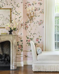 a living room filled with furniture and a fire place in front of a wallpapered wall