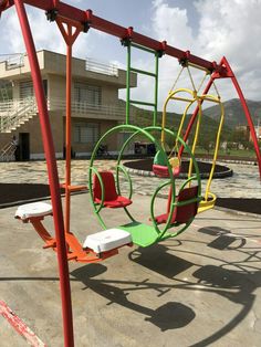 an empty playground with swings and chairs in front of a building