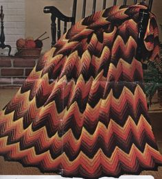 a crocheted blanket sitting on top of a chair in front of a fireplace