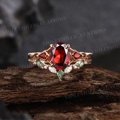 a close up view of a ring with red stones and green leaves on the side