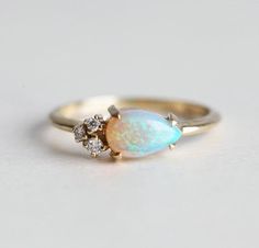 an opal and diamond ring on a white surface