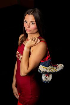 a beautiful young woman in a red top holding a pair of shoes