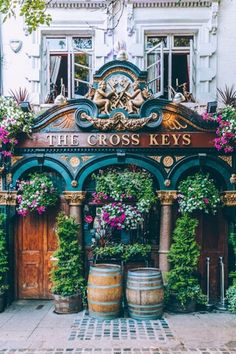 the cross keys pub in london is decorated with flowers and greenery as well as wooden barrels