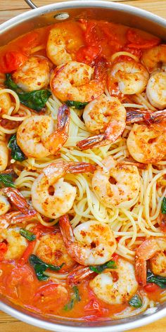 pasta with shrimp, spinach and tomato sauce in a pan on a wooden table