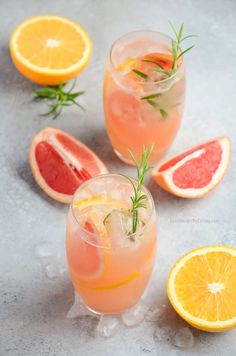 two glasses filled with grapefruit, orange and rosemary garnish on ice