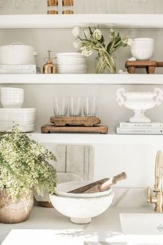 a kitchen shelf filled with lots of white dishes and flowers on top of each other