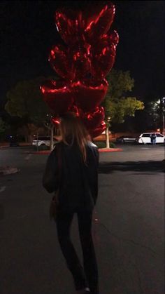 a woman walking down the street in front of a red sculpture