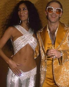 the man and woman are dressed up in disco outfits