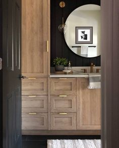 a bathroom with wooden cabinets and a round mirror on the wall above it is an area rug that matches the floor