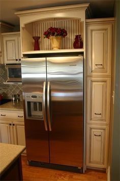 a stainless steel refrigerator in a kitchen with white cabinets