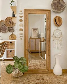 a mirror sitting on top of a wooden floor next to a vase and potted plant