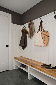 a bench with two coats hanging on the hooks and one coat rack in front of it