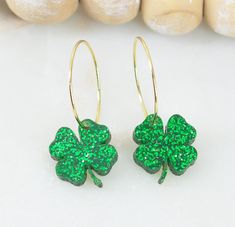 Discover the perfect pair of 4 leaf Clover statement earrings with these lightweight glitter acrylic beauties, designed to effortlessly elevate your ensemble. Crafted from premium green glitter acrylic, they offer both style and comfort, allowing you to flaunt bold, eye-catching earrings all day long. Features:   -Material: Premium Green glitter acrylic   -Size: Approximately 1.35 inches in length (measured from the top of the earring hoop)    Clover measures 15mm   -Hypoallergenic Stainless Steel earring hoop for sensitive ears Care Instructions:   -Clean gently with a microfiber cloth to remove dust   -Avoid contact with perfumes and lotions to prevent potential discoloration   -Store delicately on a jewelry stand or in a box when not in use   -Refrain from wearing in water and avoid sho Green Leaf-shaped Party Jewelry, Saint Patricks Day Earrings, Green Glitter Earrings As A Gift, Green Heart-shaped Earrings For Gifts, Festive Dual-tone Green Earrings, Four Leaf Clover Earrings, Green Heart-shaped Earrings For Valentine's Day, 4 Leaves, Clover Earrings