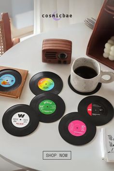 a table topped with lots of records next to a cup of coffee