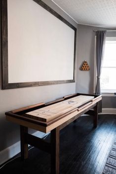 an empty room with a large white board on the wall, and a wooden table in front of it