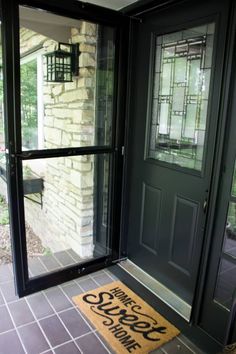 the front door is open and there is a welcome mat on the floor