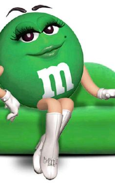 a woman sitting on top of a green couch with the letter m painted on it