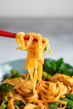 the noodles are being held up with chopsticks in a bowl full of broccoli