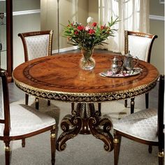 a dining room table with chairs and a vase filled with flowers on top of it