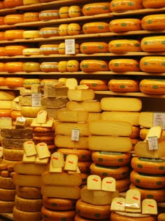 many different types of cheese stacked on shelves