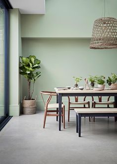 a dining room table and chairs with plants on the tables in pots next to them