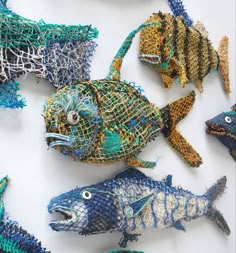 several fish made out of fishing nets on a white surface with blue and green colors