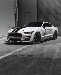 a white mustang parked in front of a garage