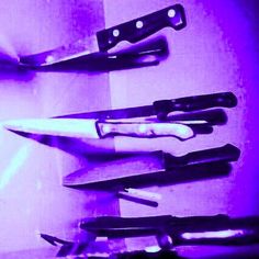 there are many different types of knifes on the counter top in this photo, one is black and purple