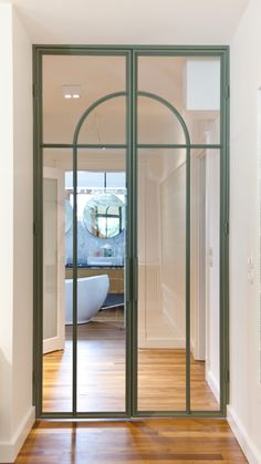 an open door leading to a bathroom with a bathtub in the background and wooden floors