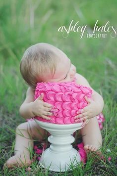 a baby sitting in the grass with a pink blanket on it's back