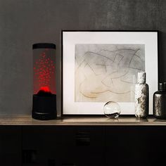 there is a painting and some bottles on the table next to each other with red light coming from them