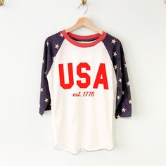 LIMITED QUANTITIES AVAILABLE! SIZE SMALL ONLY USA est. 1776 Patriotic 4th of July Shirt with American Flag Star Sleeves The perfect American shirt for any Independence day party! These run true to size. We recommend sticking with your normal shirt size, unless you are in between sizes or prefer a looser fit then order a size up. Red Star Print Crew Neck Tops, Patriotic Red Tops With Star Print, Patriotic Red Star Print Top, Patriotic Star Print Top For Independence Day, Red Patriotic Top With Star Print, Red Patriotic Star Print Top, Red Cotton T-shirt With Star Print, Patriotic Screen Print Tops For Memorial Day, 4th Of July Red Star Print Tops