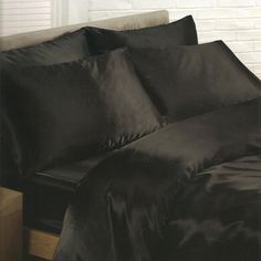 a bed with black sheets and pillows on it