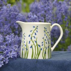 a white pitcher with blue flowers in the background