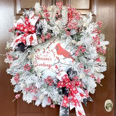 a christmas wreath with cardinals and snowflakes hanging on a front door decorated for the holiday season